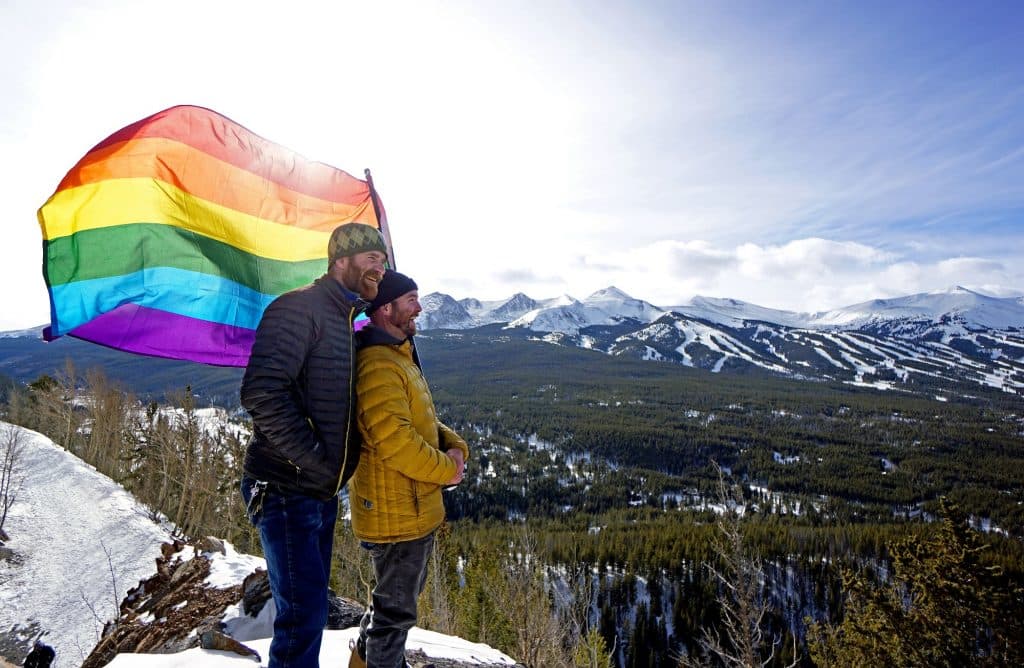 A couple with a Pride flag overlooking the mountains in Breckenridge