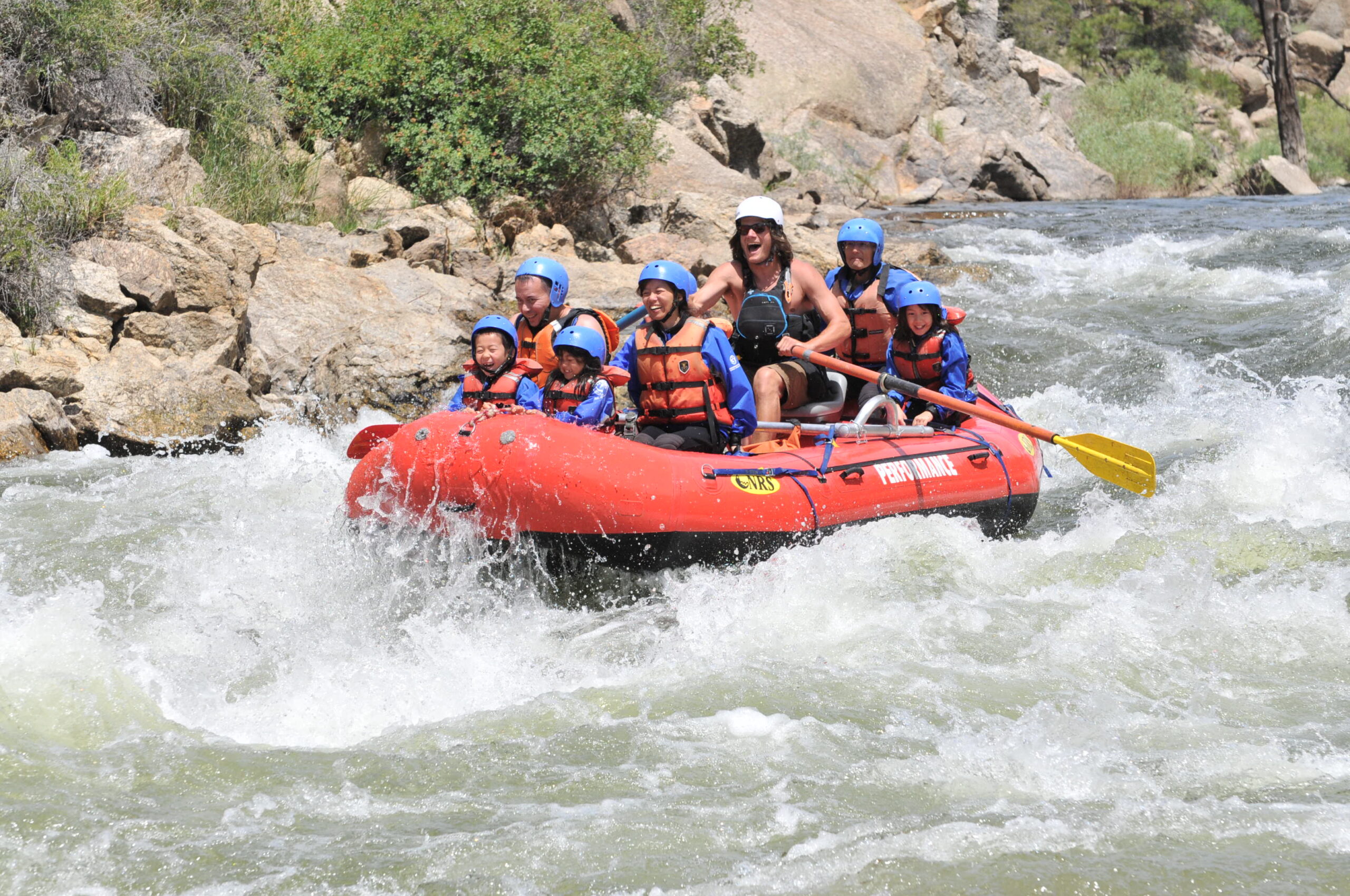 A family smiling on a raft going through rapids in the Brown Canyon in Colorado.