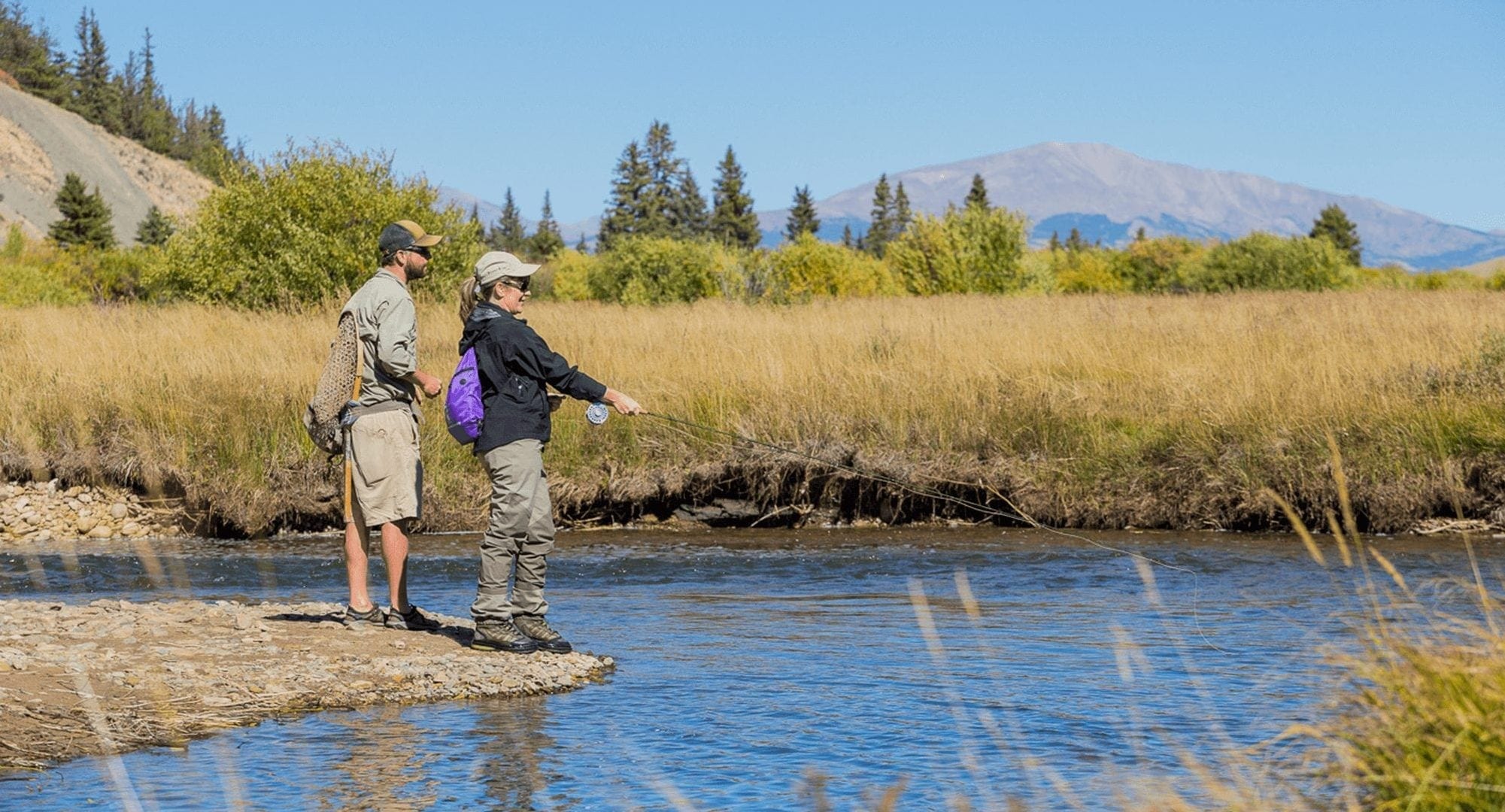 A couple fly fishing on a summer day in Park County, CO