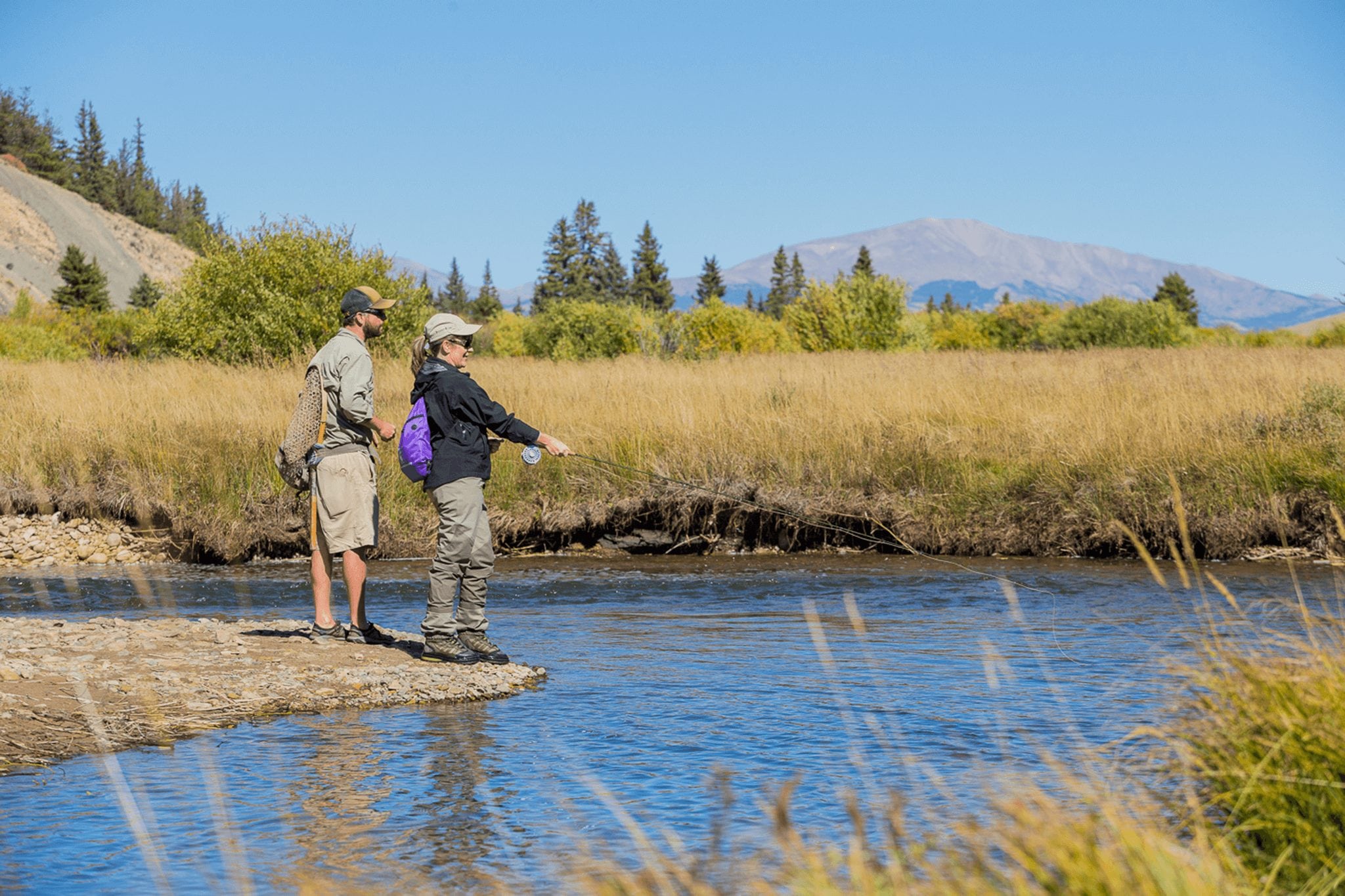 A couple fly fishing on a summer day in Park County, CO