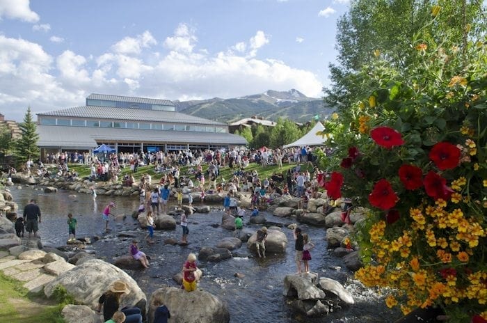 A crowd of people near the Riverwalk Center on the Blue River in Breckenridge during summer.