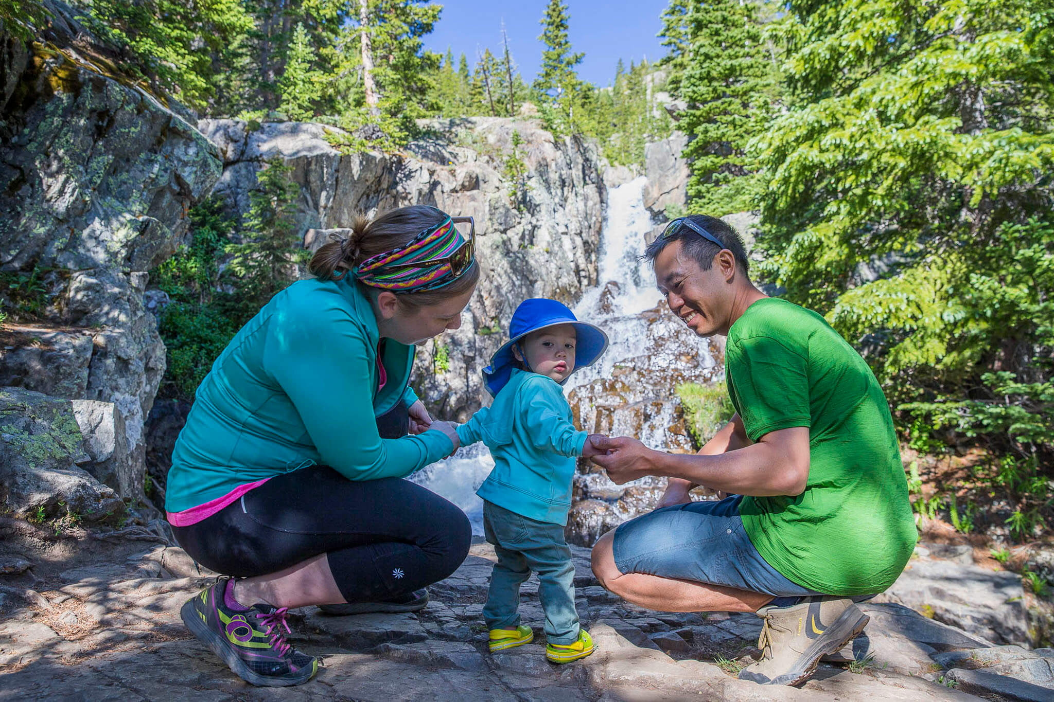 Parents checking their child's clothing at a waterfall