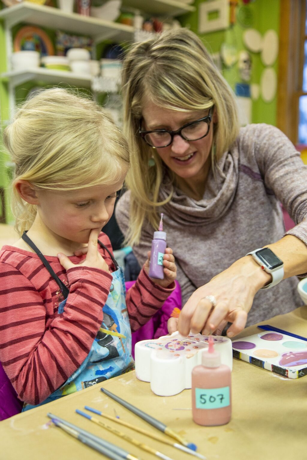 woman helping kid paint