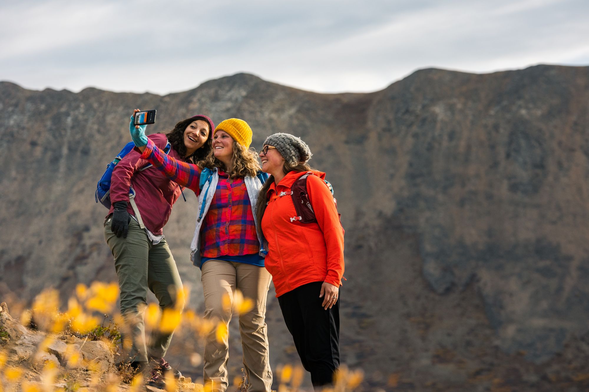 Three friends taking a selfie during fall in Breckenridge, Colorado, with mountain scenery in the background.