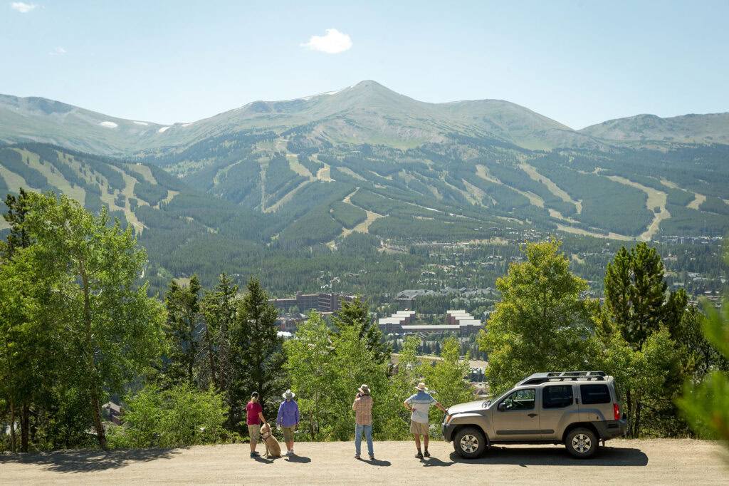 four hikers and their dog look at mountain view