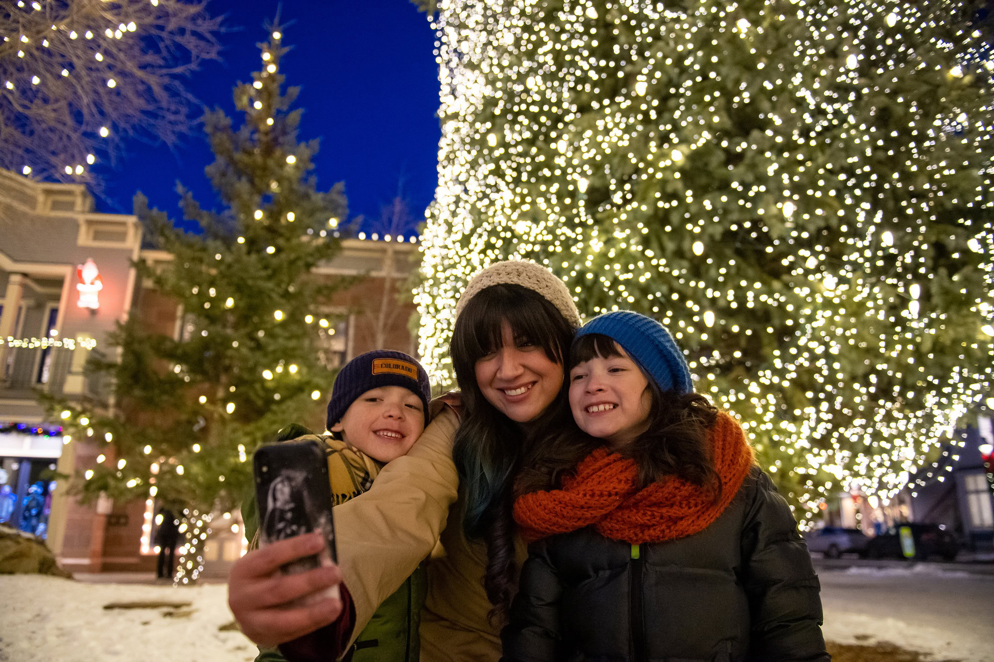 family taking a selfie in front of a tree full of lights