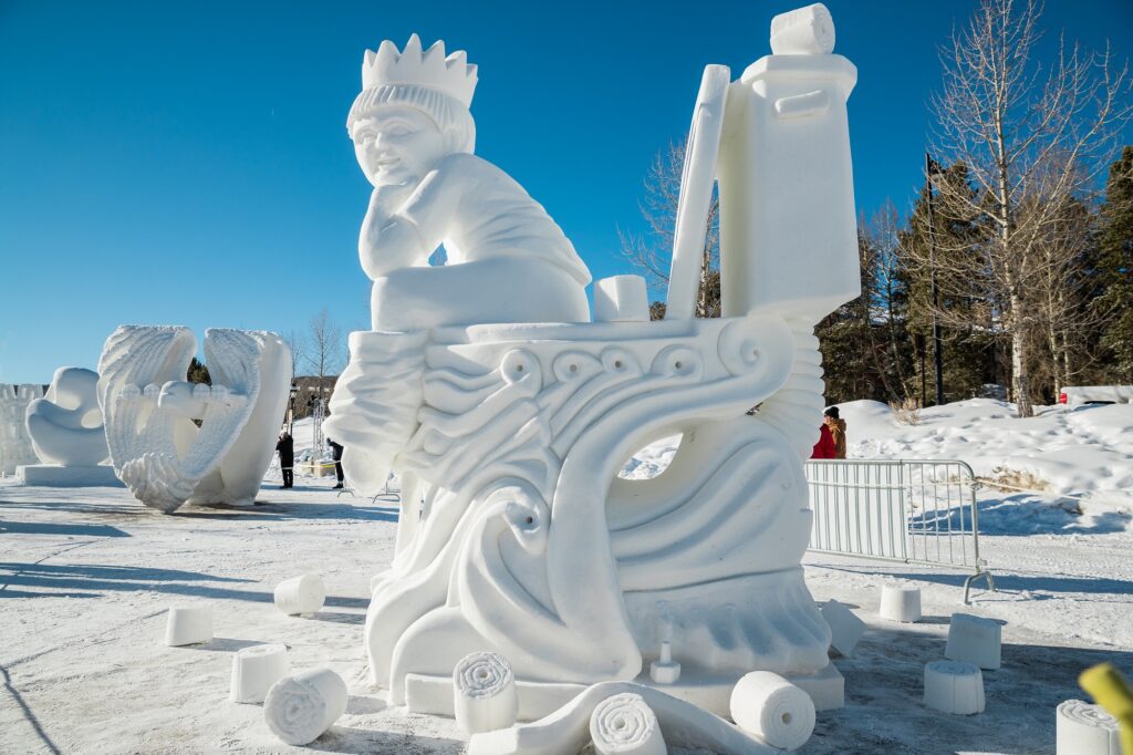 ornate snow sculpture of a kid on a toilet