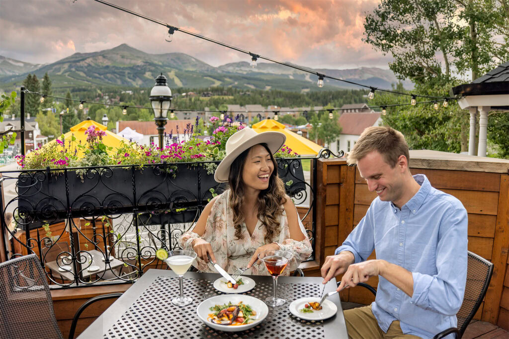 A couple enjoying dinner on a patio with mountains in the background