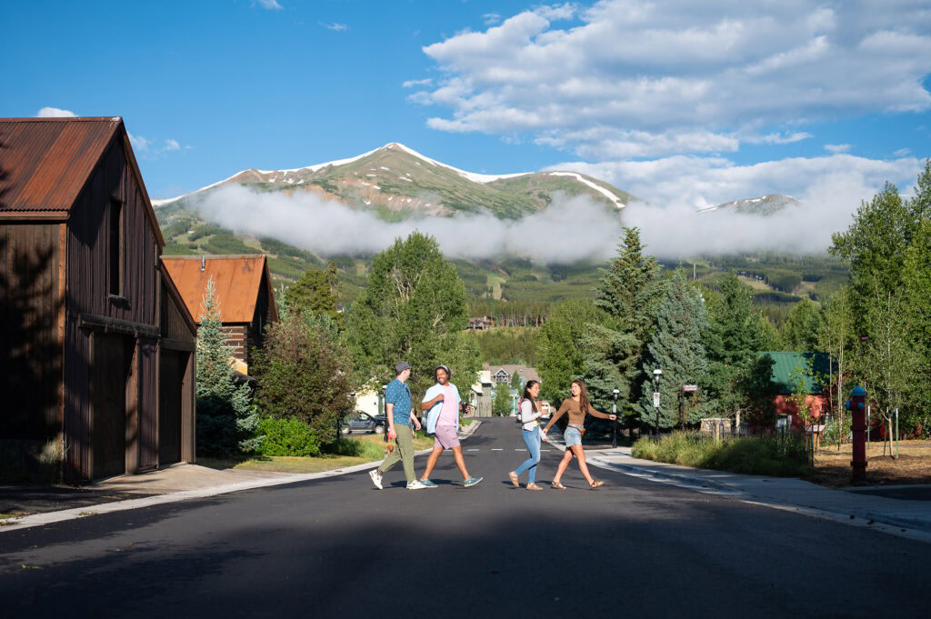 group of people crossing a street with mountains in the background