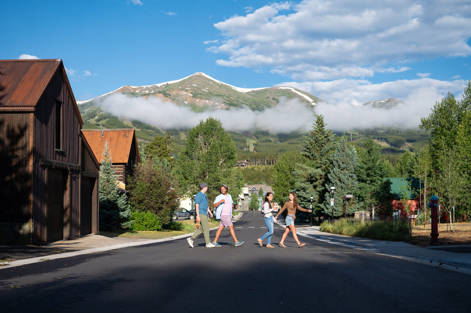 group of people crossing a street with mountains in the background