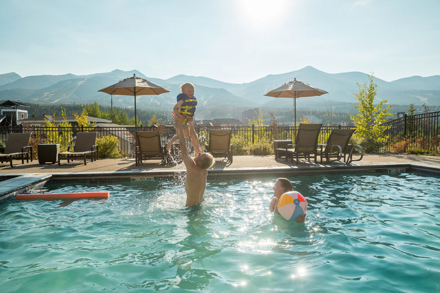 family playing in the pool on a sunny day