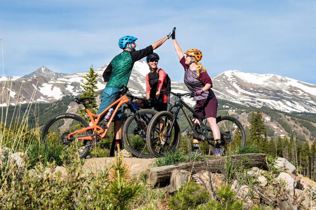 Three people on mountain bikes giving each other a high five